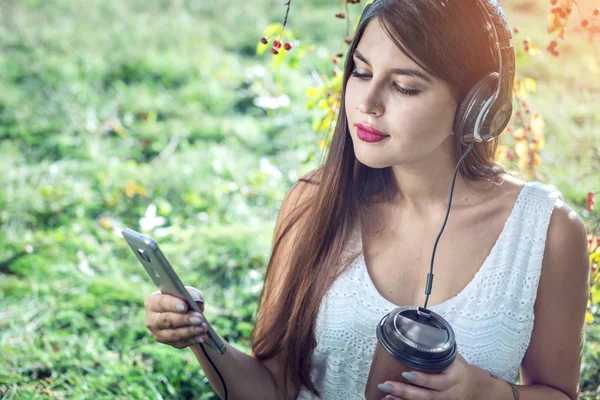 Kobieta, słuchanie muzyki w telefonie, noszenie słuchawek w słoneczny dzień. Koncepcja kształcenia Audiobooki, student — Zdjęcie stockowe