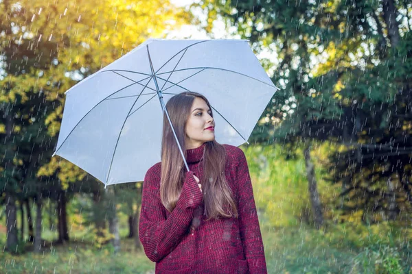 Jovem feliz andando em um parque ensolarado com um guarda-chuva branco na chuva. Conceito de estações e clima de outono — Fotografia de Stock