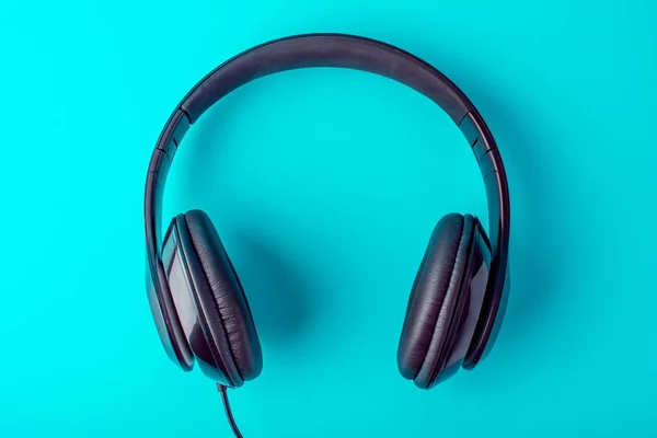 Auriculares negros grandes y un estilo minimalista sobre un fondo azul — Foto de Stock