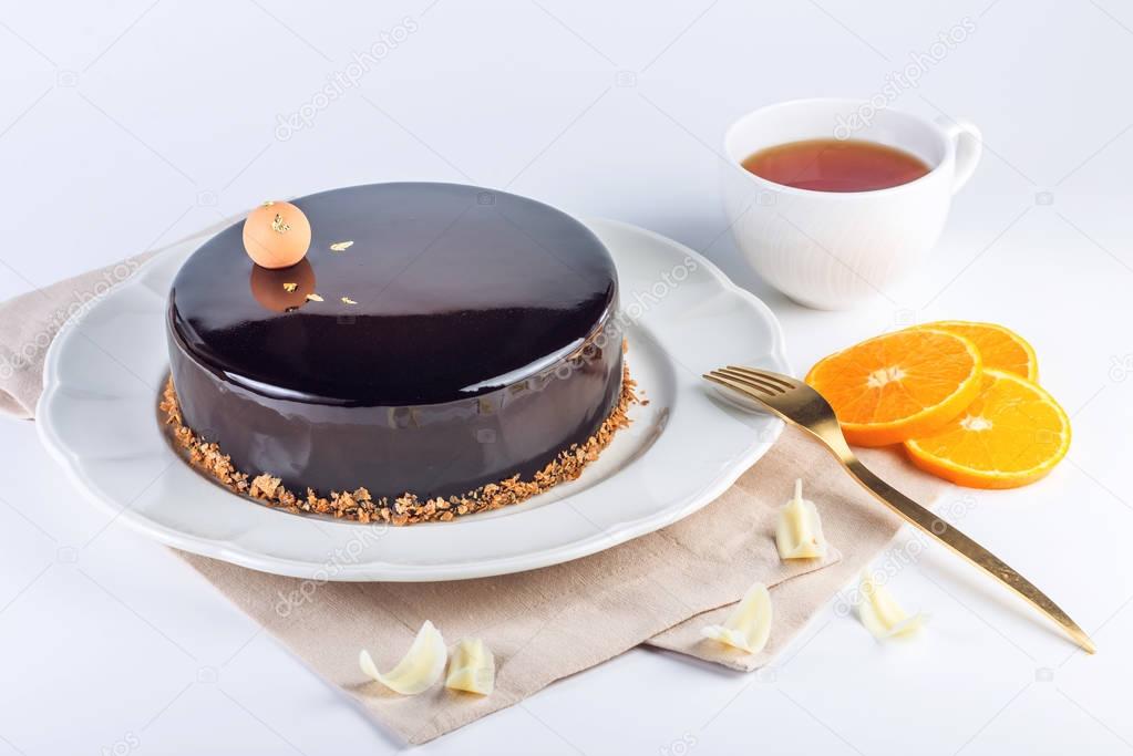 Beautiful truffle cake with orange covered with glossy dark chocolate glaze. Concept design desserts