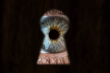 Kadın mavi göz anahtar deliği arıyor. Röntgencilik, merak, Stalker, gözetim ve güvenlik kavramı