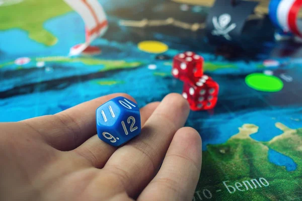 Hand würfelt die blauen Würfel auf der Weltkarte des Spielfeldes handgemachte Brettspiele mit einem Piratenschiff — Stockfoto