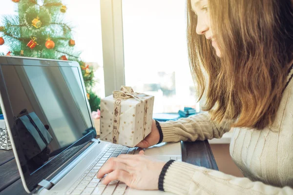 Mujer con un regalo para la Navidad y la reserva de año nuevo a través de Internet en el ordenador portátil. Concepto de venta de vacaciones — Foto de Stock