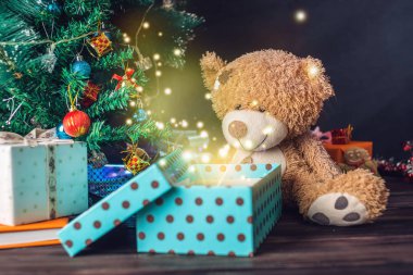 Bir oyuncak ayı bir hediye arka plan parlak Noel ağacı açılır. Yılbaşı gecesi Magic kavramı