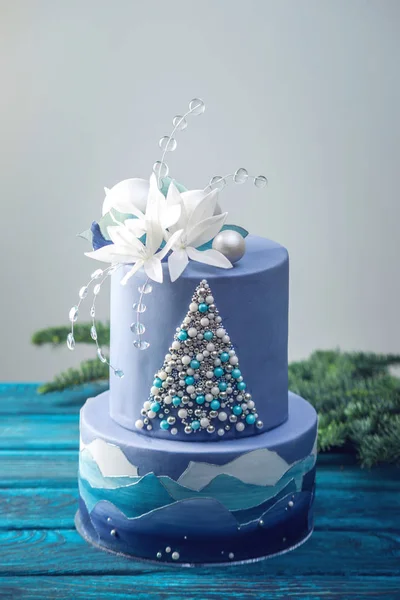 Tiered cake the blue cake with the image of a Christmas tree and white flowers on top. Concept of festive desserts — Stock Photo, Image