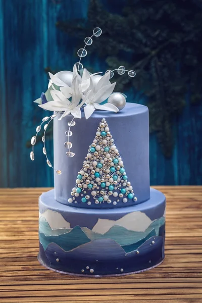 Tarta estratificada la tarta azul con la imagen de un árbol de Navidad y flores blancas en la parte superior. Concepto de postres festivos —  Fotos de Stock