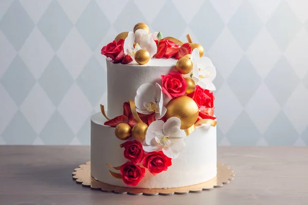 Hermoso pastel de boda blanco de dos niveles decorado con rosas rojas. Concepto de elegantes postres navideños —  Fotos de Stock