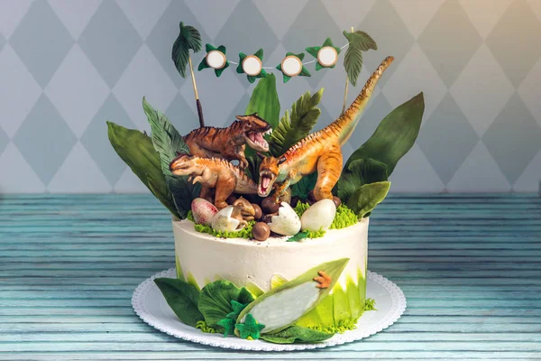 Children's holiday fehér torta díszítik, dinoszauruszok, a jura időszak dzsungelben. Koncepció ötleteket desszertek gyerekeknek — Stock Fotó