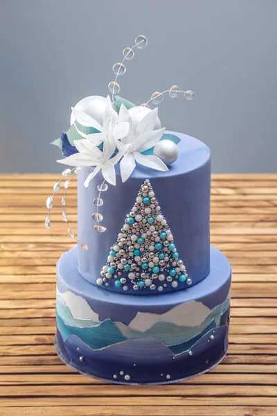 Tarta estratificada la tarta azul con la imagen de un árbol de Navidad y flores blancas en la parte superior. Concepto de postres festivos —  Fotos de Stock