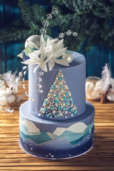 Tarta estratificada la tarta azul con la imagen de un árbol de Navidad y flores blancas en la parte superior. Concepto de postres festivos —  Fotos de Stock