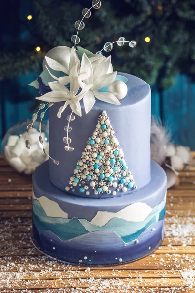 Tarta estratificada la tarta azul con la imagen de un árbol de Navidad y flores blancas en la parte superior. Concepto de postres festivos —  Fotos de Stock