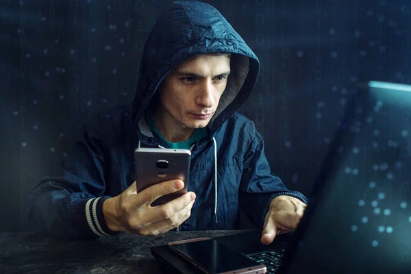 Чоловічий хакер використовує мобільний телефон, щоб зламати систему. Концепція кіберзлочинності та злому електронних пристроїв — стокове фото