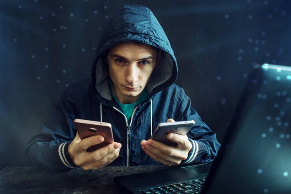 Peretas pria menggunakan ponsel untuk meretas sistem. Konsep kejahatan cyber dan peretasan perangkat elektronik — Stok Foto