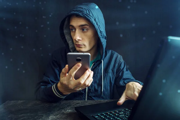 Male hacker uses the mobile phone to hack the system. Concept of cyber crime and hacking electronic devices