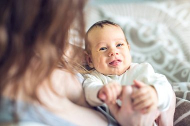 Yatak odasında erkek gülümseyen bir bebek tutan mutlu bakım anne. Annelik ve aile değerleri hassasiyet kavramı