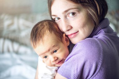 Yatak odasında erkek gülümseyen bir bebek tutan mutlu bakım anne. Annelik ve aile değerleri hassasiyet kavramı