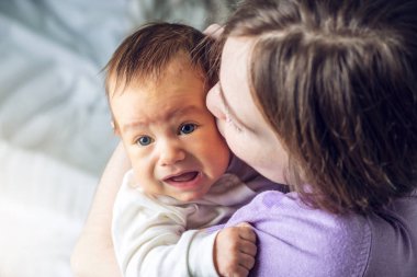 Mutlu erkek gülümseyen bir bebek tutan anne ve onu öper. Annelik ve aile değerleri hassasiyet kavramı