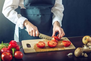 Siyah önlük Şef domates kes. Yemek pişirmek için çevre dostu ürünler kavramı