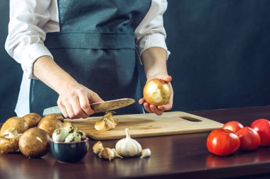 Siyah önlük Şef bir soğan bir bıçakla keser. Yemek pişirmek için çevre dostu ürünler kavramı