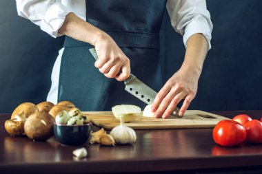 Siyah önlük Şef bir soğan bir bıçakla keser. Yemek pişirmek için çevre dostu ürünler kavramı