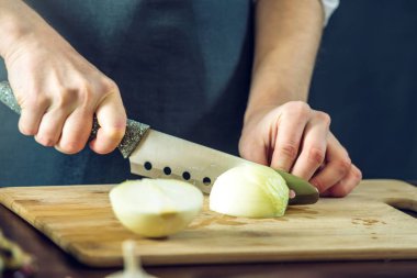 Siyah önlük Şef bir soğan bir bıçakla keser. Yemek pişirmek için çevre dostu ürünler kavramı