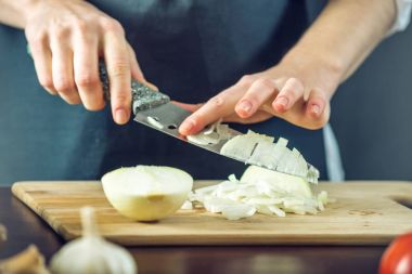Siyah önlük Şef bir soğan bir bıçakla keser. Yemek pişirmek için çevre dostu ürünler kavramı