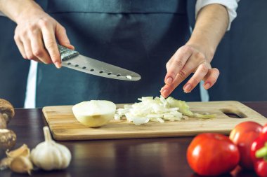 Siyah önlük Şef bir soğan bir bıçakla keser. Yemek pişirmek için çevre dostu ürünler kavramı