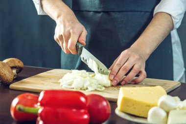 Siyah önlük Şef bir soğan bir bıçakla keser. Yemek pişirmek için çevre dostu ürünler kavramı