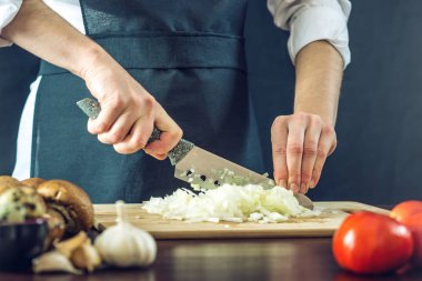 Siyah önlük Şef bir soğan bir bıçakla keser. Yemek pişirmek için çevre dostu ürünler kavramı