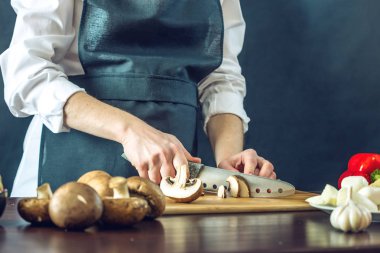Siyah önlük Şef mantar bıçakla keser. Yemek pişirmek için çevre dostu ürünler kavramı