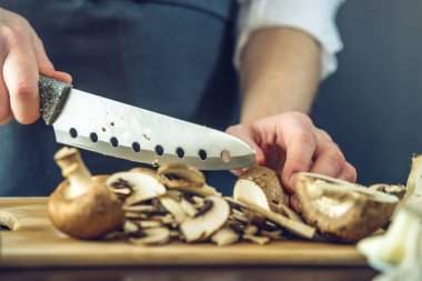 Siyah önlük Şef mantar bıçakla keser. Yemek pişirmek için çevre dostu ürünler kavramı