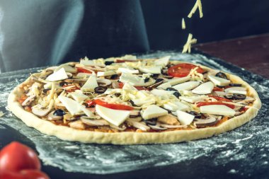 Ev yapımı büyük vejetaryen pizza malzemelerle karanlık bir masada pişirmeye hazır
