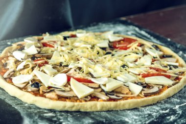 Ev yapımı büyük vejetaryen pizza malzemelerle karanlık bir masada pişirmeye hazır