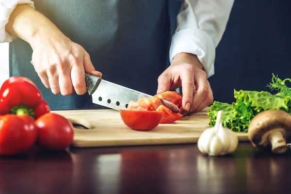 Siyah önlük Şef sebze keser. Yemek pişirmek için çevre dostu ürünler kavramı
