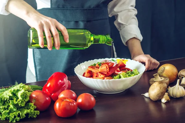 El chef en delantal negro hace una ensalada de verduras. Concepto de productos ecológicos para cocinar — Foto de Stock