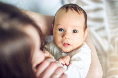 Yatak odasında erkek gülümseyen bir bebek tutan mutlu bakım anne. Annelik ve aile değerleri hassasiyet kavramı