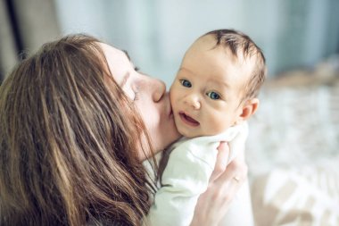 Yatak odasında erkek bebek tutan mutlu bakım anne. Annelik ve aile değerleri hassasiyet kavramı