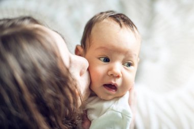 Yatak odasında erkek bebek tutan mutlu bakım anne. Annelik ve aile değerleri hassasiyet kavramı