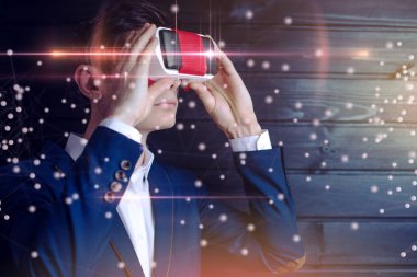 Takım elbiseli çekici genç işadamı, karanlık bir arka plan üzerinde renkli sanal gerçeklik gözlük kullanır. Bizim hayatımızda fütüristik ve modern teknoloji kavramı