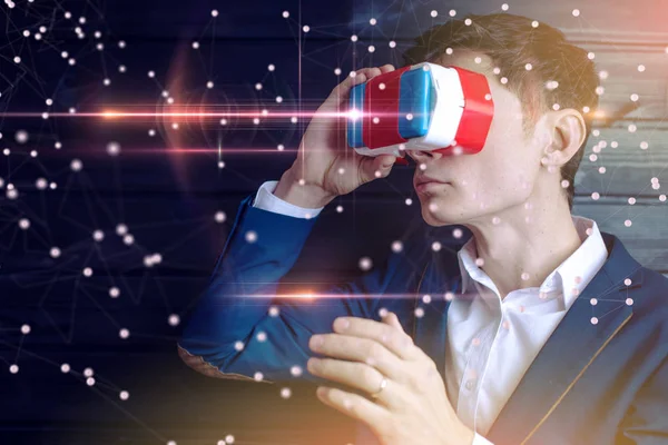 Attractive Young businessman in suit uses a colorful virtual reality glasses on a dark background. The concept of futuristic and modern technology in our lives