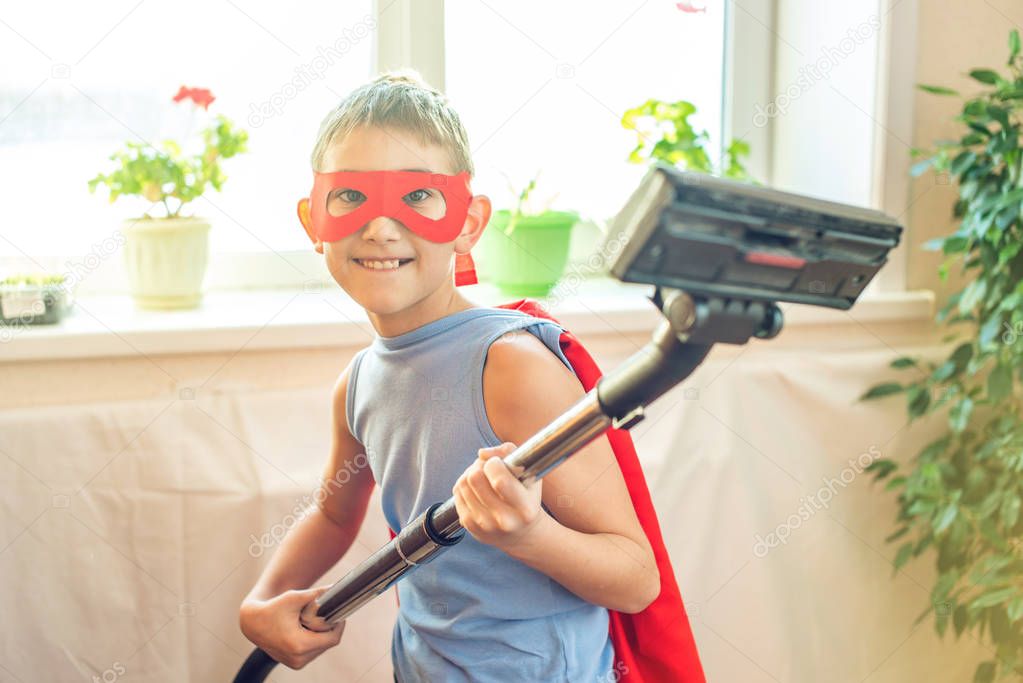 Boy child superhero costume playing is cleaning the house. The concept of children helping their parents in the form of a game