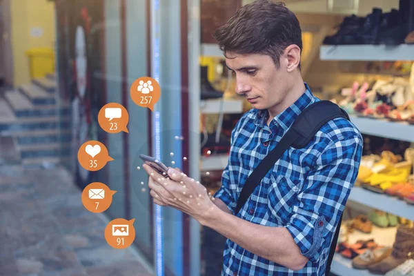 A young man uses the phone for entertainment and communication on the Internet and viewing notifications in the form of icons. The concept of social network and media