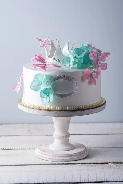 Krásný bílý dort zdobí růžové a tyrkysové květy a princezna koruny. Koncept dezertů pro dívky — Stock fotografie