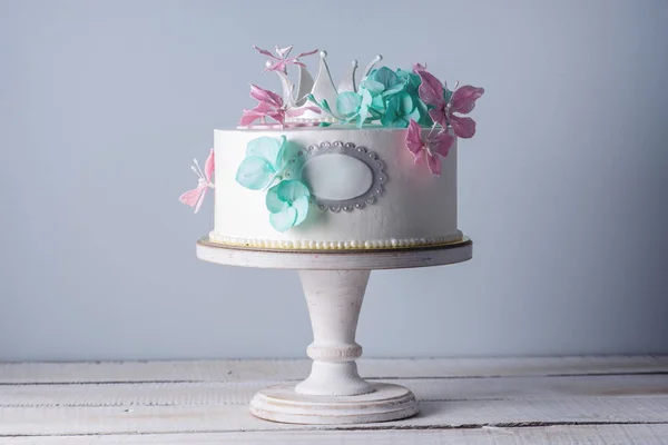 Hermoso pastel blanco decorado con flores de color rosa y turquesa y una corona de princesa. Concepto de postres para niñas — Foto de Stock