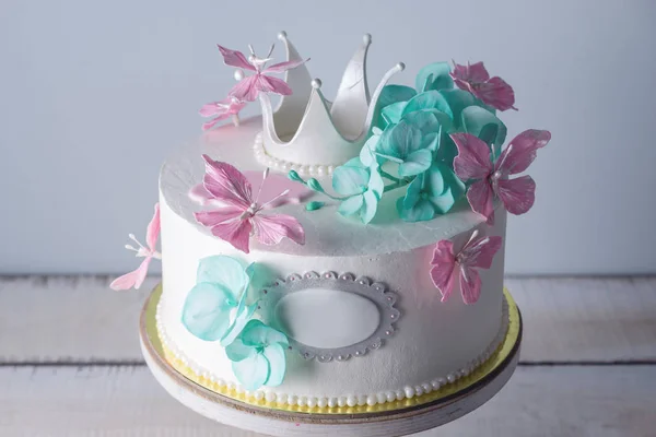 Beautiful white cake decorated with pink and turquoise flowers and a Princess crown. Concept of desserts for girls — Stock Photo, Image