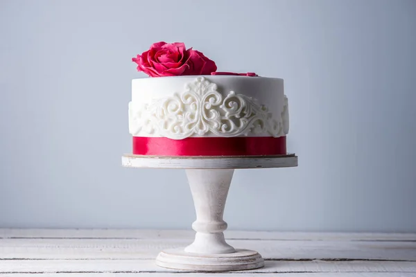 Bolo de casamento branco bonito decorado com flores rosas vermelhas e fita. Conceito de sobremesas de férias elegantes — Fotografia de Stock