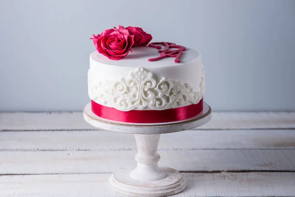 Bolo de casamento branco bonito decorado com flores rosas vermelhas e fita. Conceito de sobremesas de férias elegantes — Fotografia de Stock