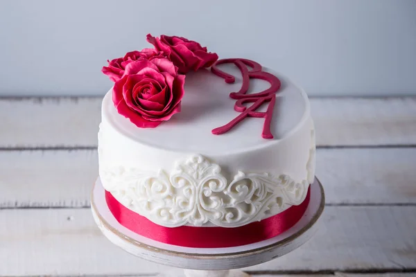 美丽的白色婚礼蛋糕装饰着鲜花红玫瑰和丝带。优雅假日甜点概念 — 图库照片
