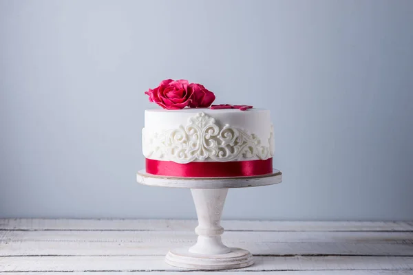 Bolo de casamento branco bonito decorado com flores rosas vermelhas e fita. Conceito de sobremesas de férias elegantes — Fotografia de Stock