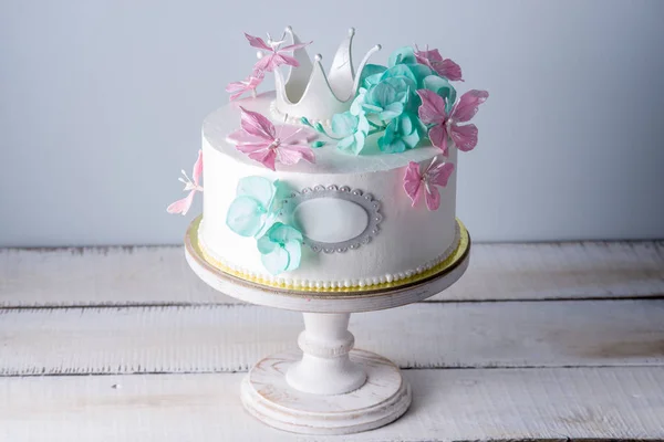 Hermoso pastel blanco decorado con flores de color rosa y turquesa y una corona de princesa. Concepto de postres para niñas —  Fotos de Stock